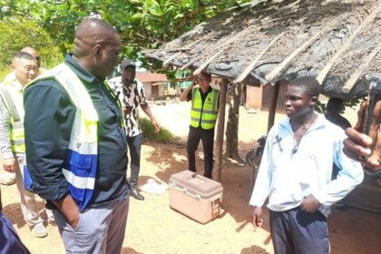 Governs Agbodza (left), Minister of Roads and Highways, interacting with some community members at Nsuano, along the Elubo-Enchi road